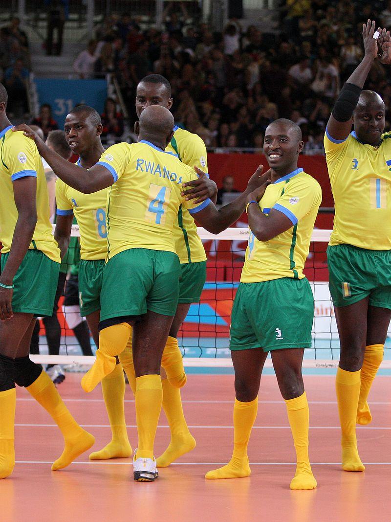 Six men celebrating on a volleyball field.