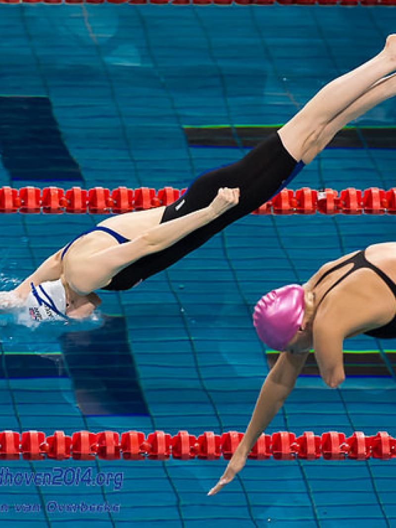 Two female athletes dive into the pool at the 2014 IPC Swimming European Championships
