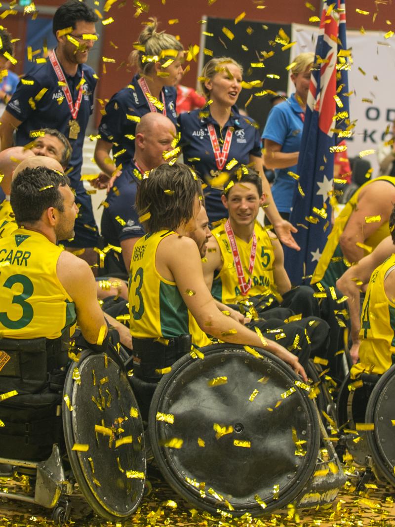 Men in wheelchairs with a big championships trophy