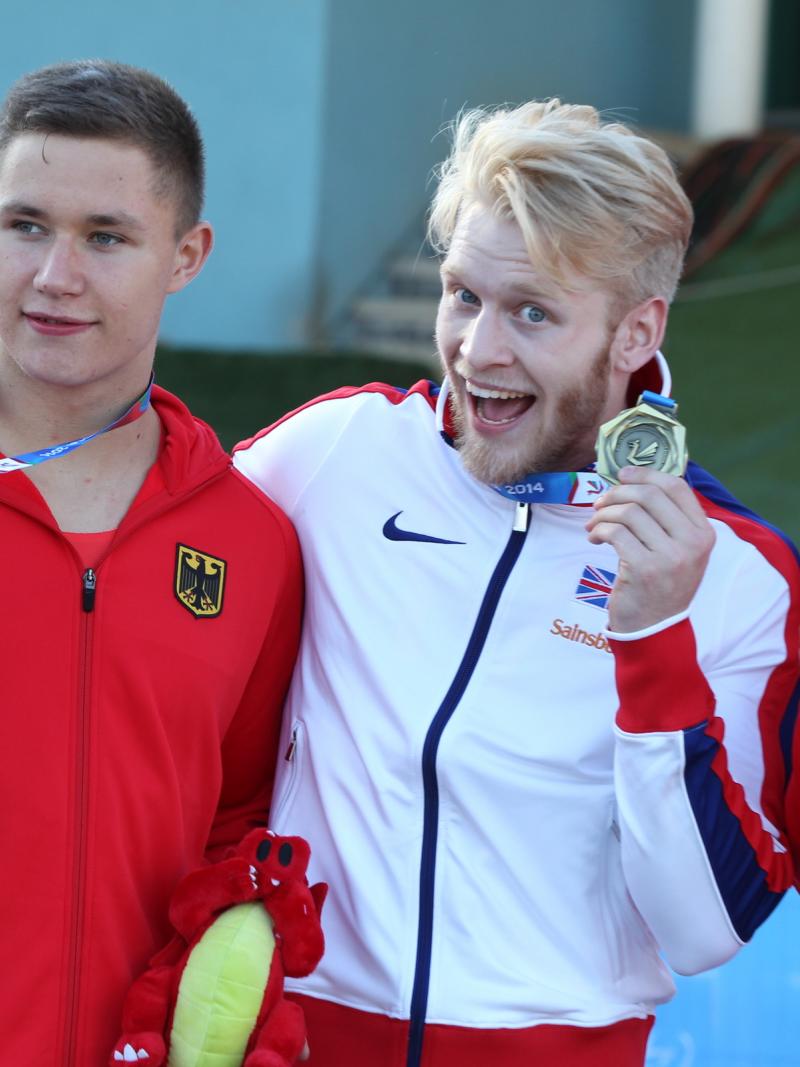 3 upper bodies of athletes on the podium, posing and showing their medals.