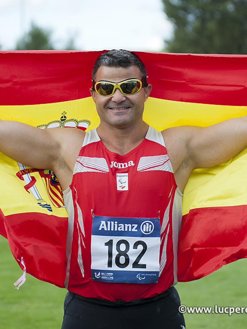 Man with a spanish flag celebrating on a field of play in a stadium