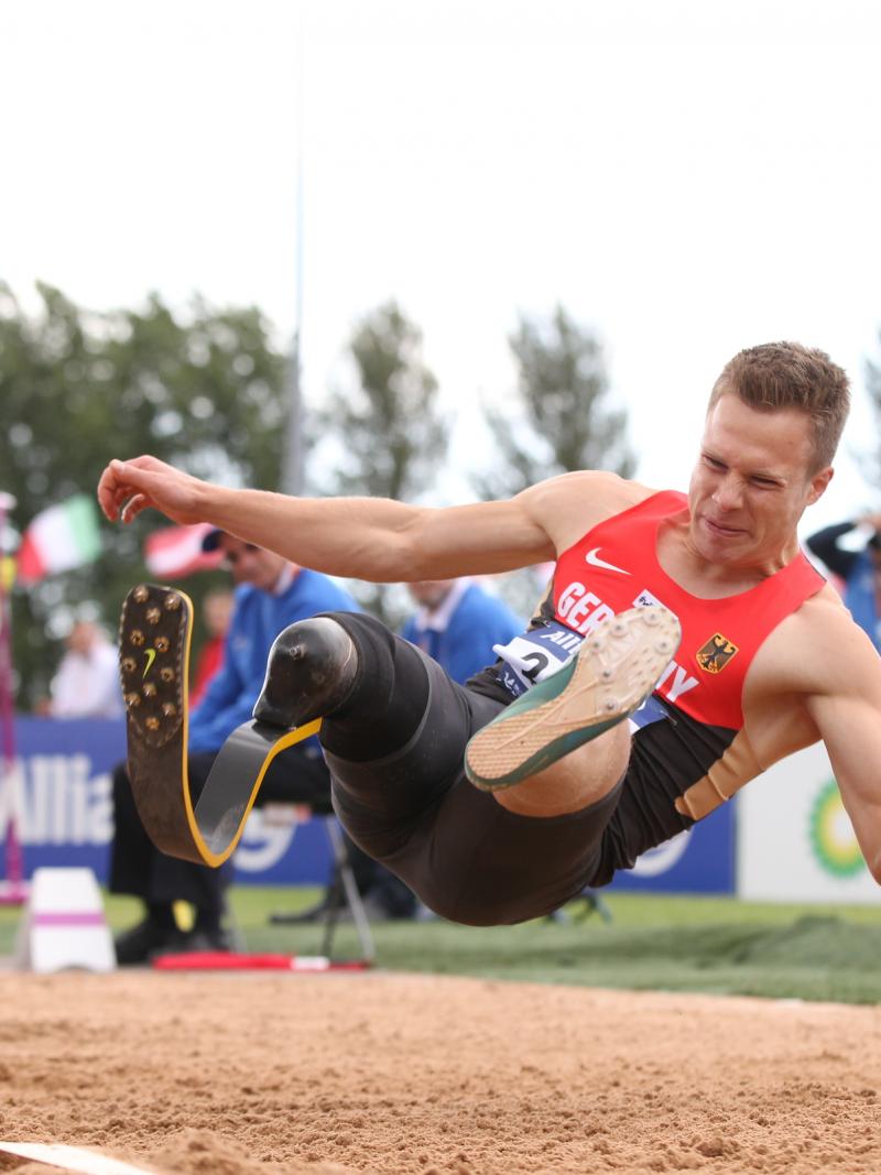 Man in the long jump right before landing in the sand