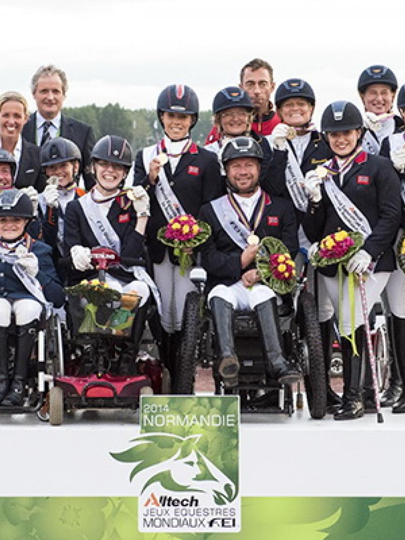 A number of jockeys standing on a podium holding flowers