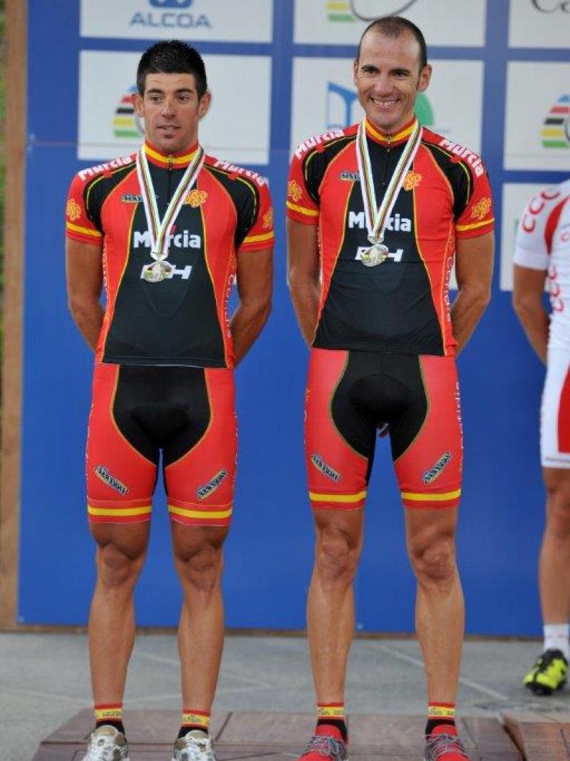 Two men stand on a podium with their medals