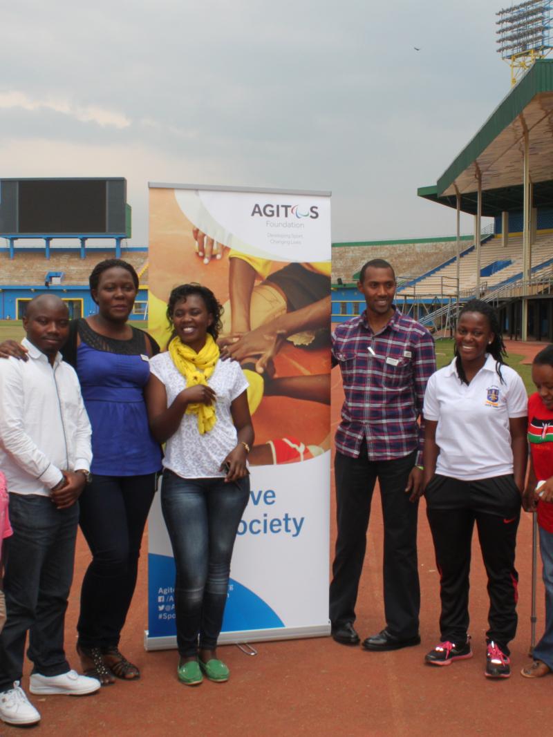 A group of people pose in front of an Agitos Foundation pull-up