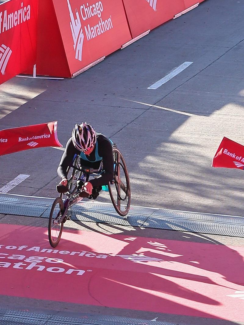 Women in racing wheelchair crossing a finish line