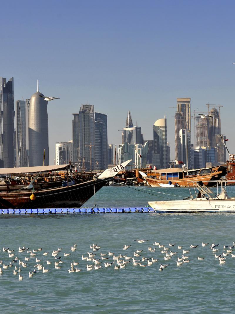 Wooden boat in the water, skyscrapers in the background