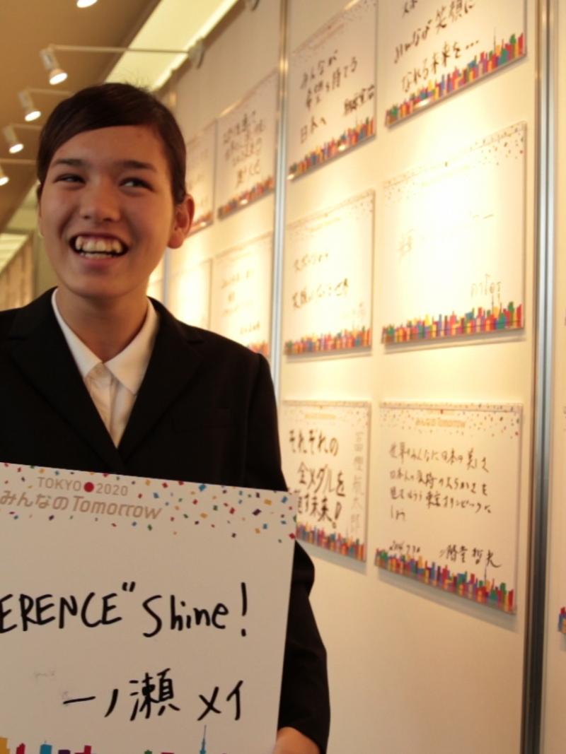 Japanese swimmer Mei Ichinose holds a sign where it is written "Make difference shine"