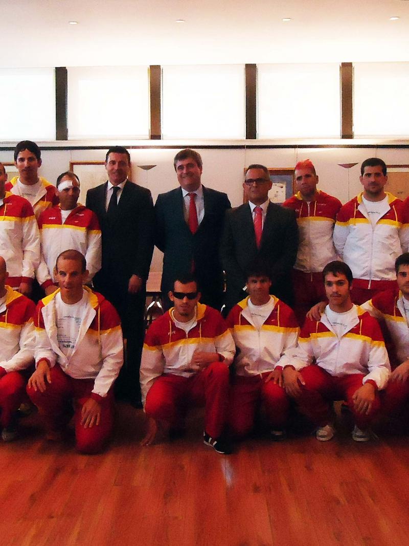 Group shot of a football team in training suits with six people in business clothes.