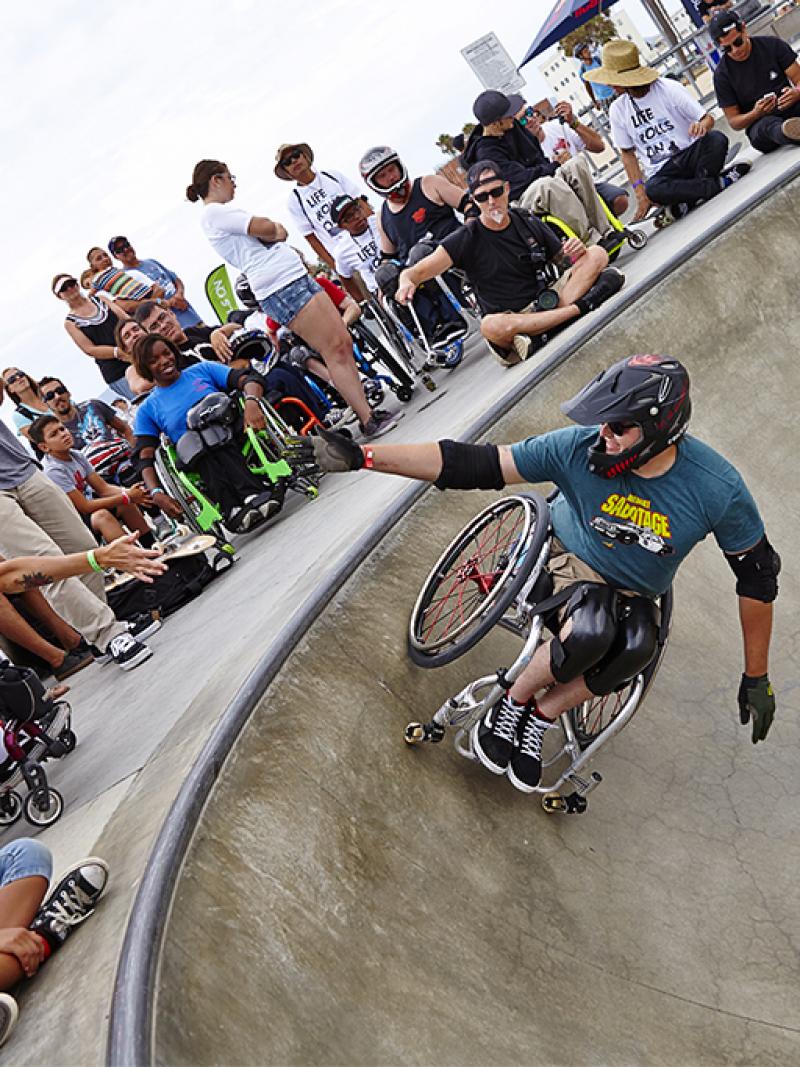 Man in wheelchair doing a stund in a halfpipe
