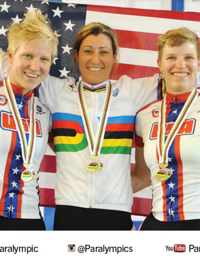 Three women on a podium, smiling to the camera