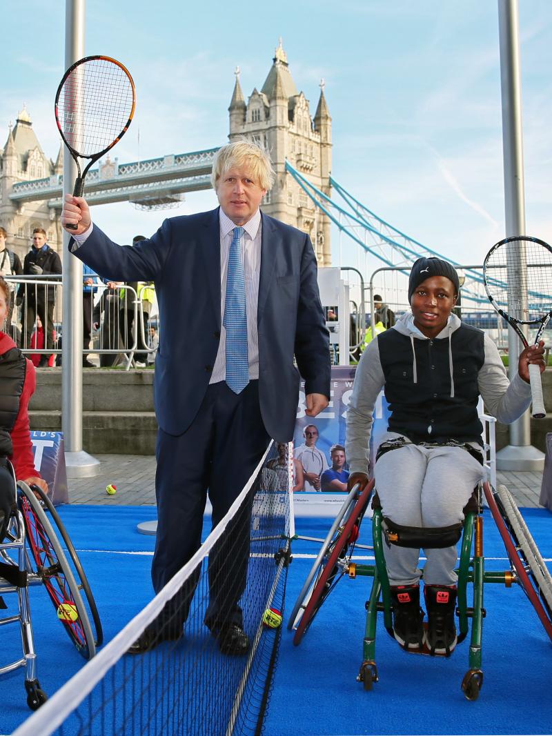 three wheelchair tennis players and the Mayor of London holding tennis rackets up in front of London Bridge