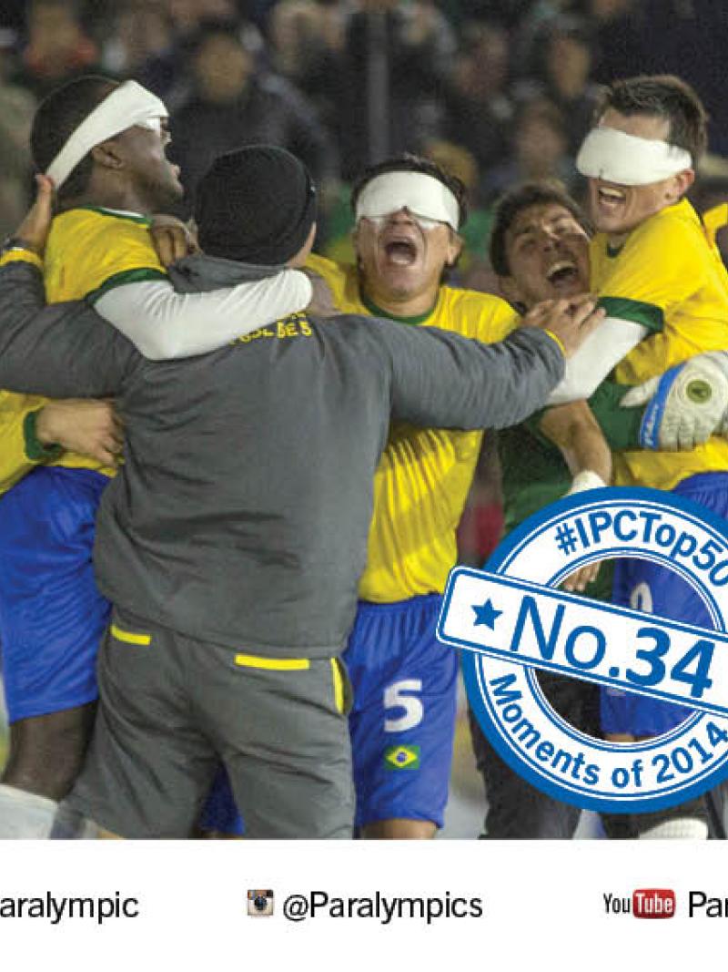 A group of five men, three blindfolded and wearing football shirts, jump up and hug in celebration