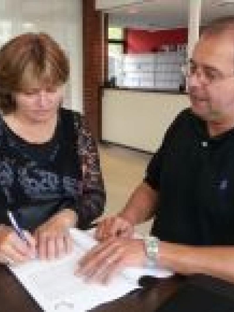Man and woman sign a form standing on a table