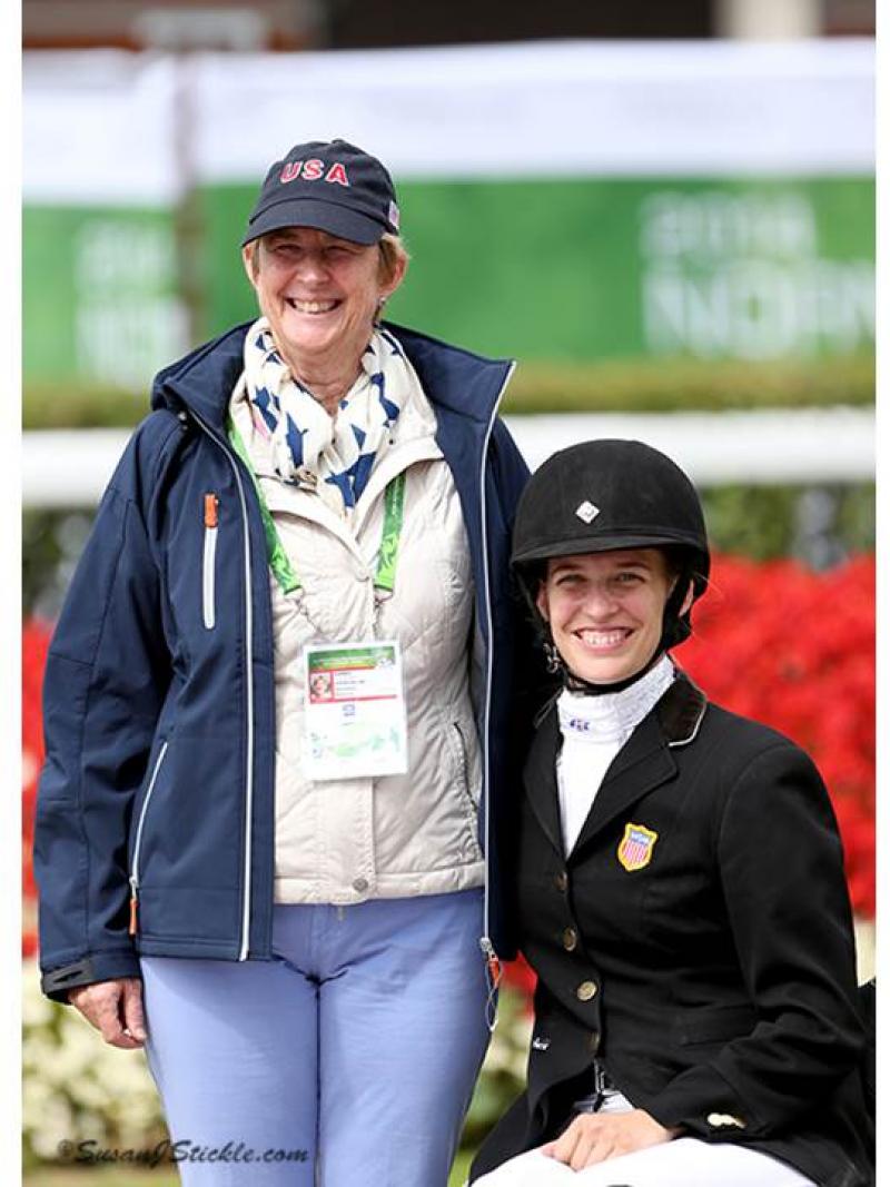 Two women posing for a photo, one with riding clothes