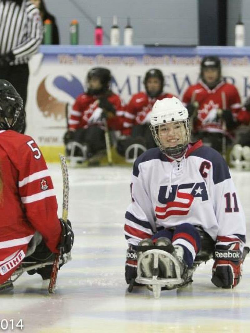 Young girl in a sled on the ice, smiling to the camera