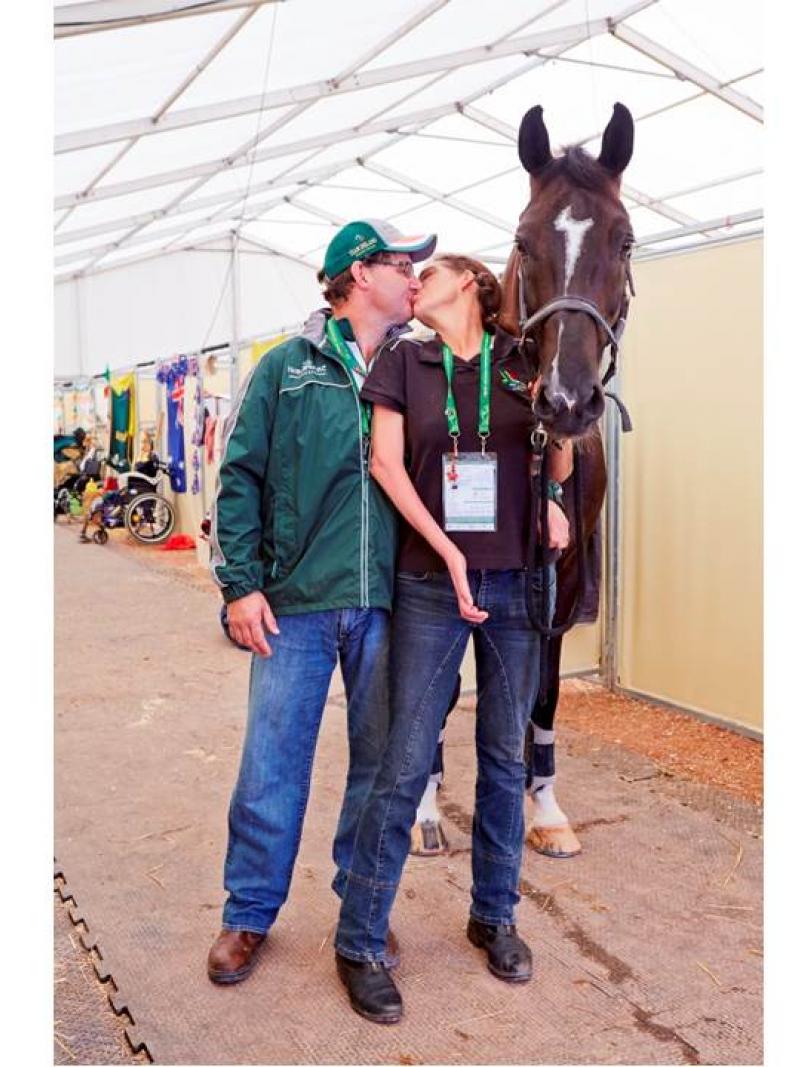 Man and women kissing, a black horse stands next to them.