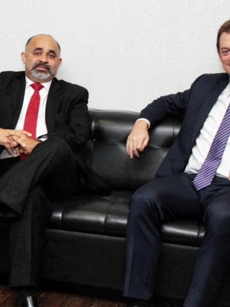 Two men in chairs smiling to the camera