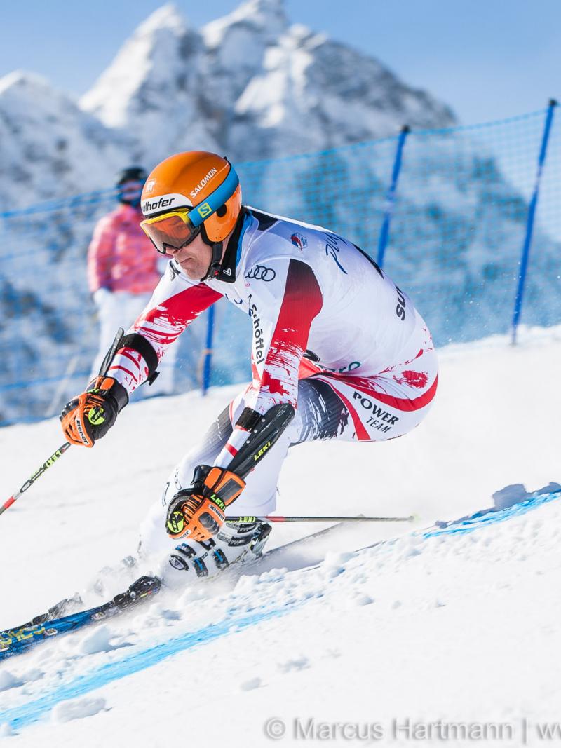 Man in race suit passing a gate on a ski slope