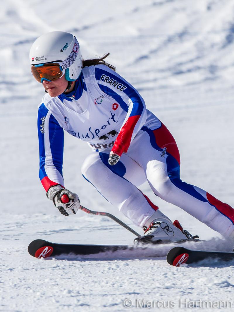 Female skier in racing suit passing a gate on a ski slope