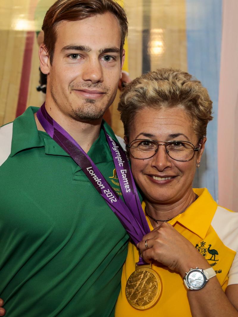 Women and man pose with a medal