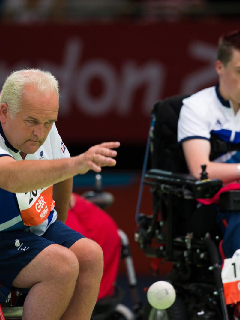 Two men in wheelchairs on a boccia field of play