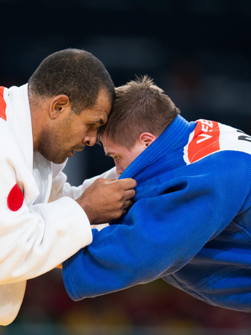 Antonio Tenorio and Vladimir Fedin hold on to each other with heads bowed close together, locked in battle