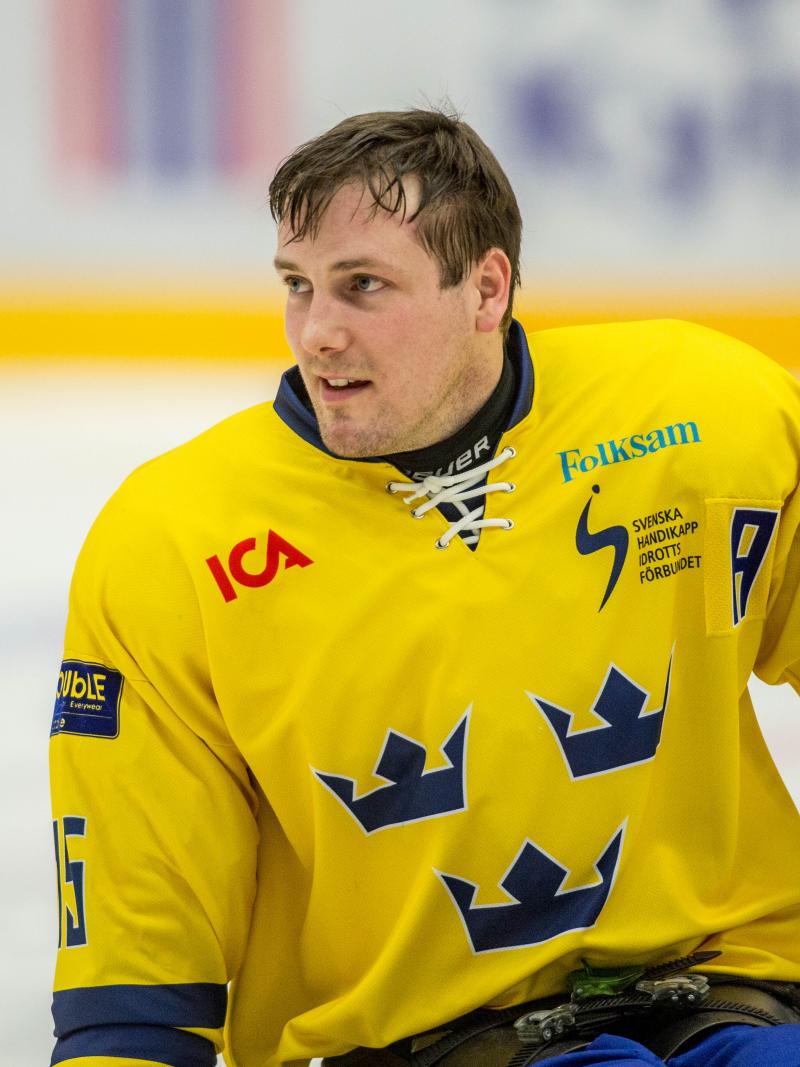 Swedish Para ice hockey player in his yellow Sweden jersey