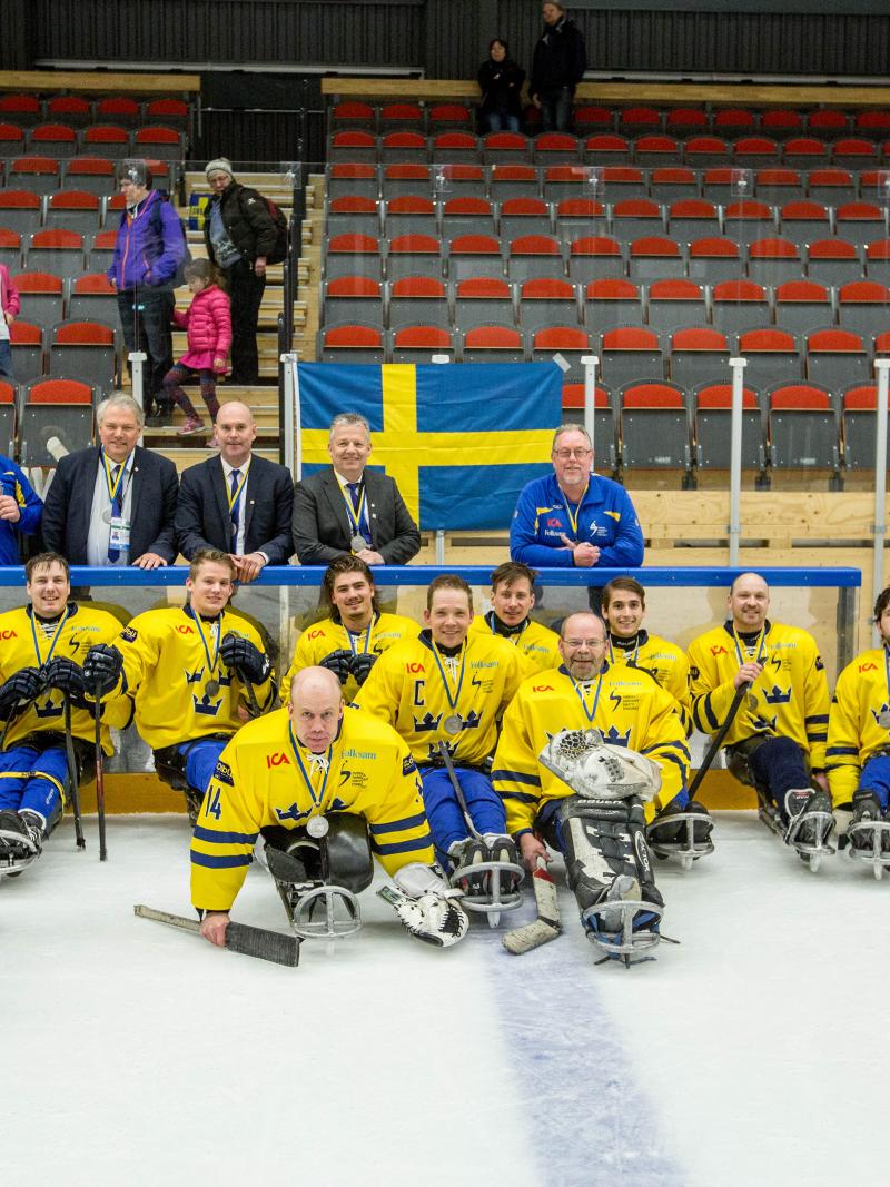 a group of Para ice hockey players on the ice with their medals