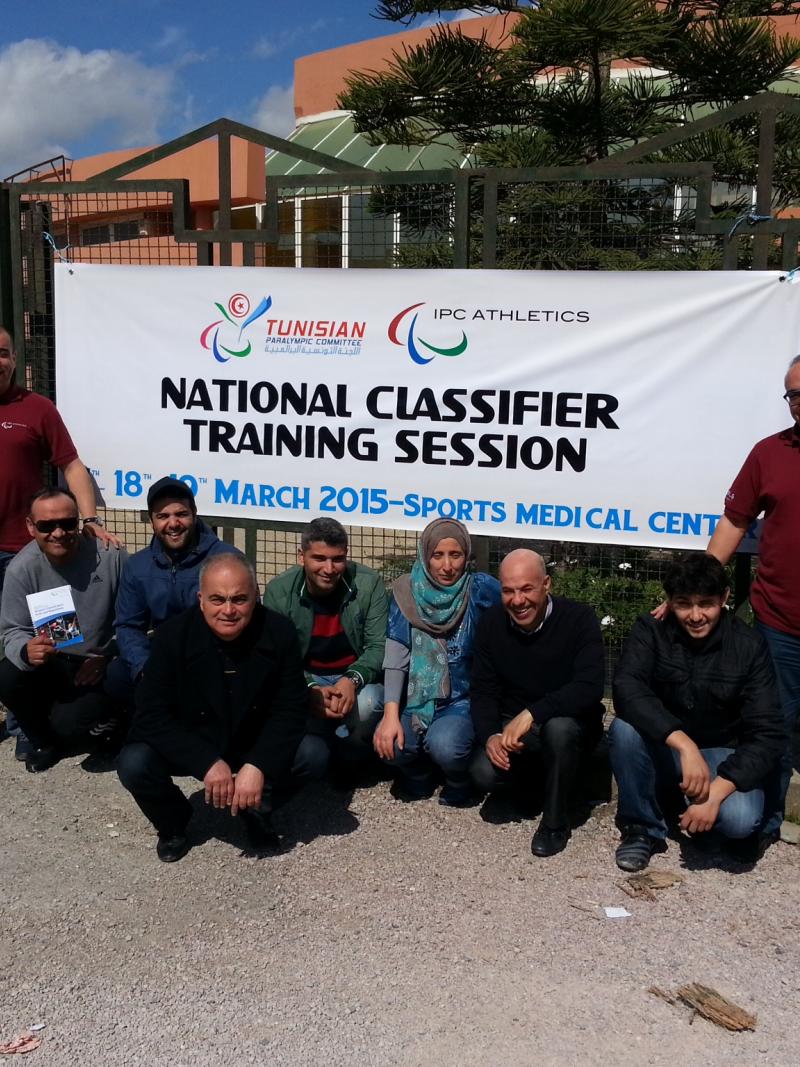 A group of people pose in front of an IPC Athletics banners in Tunis, Tunisia.