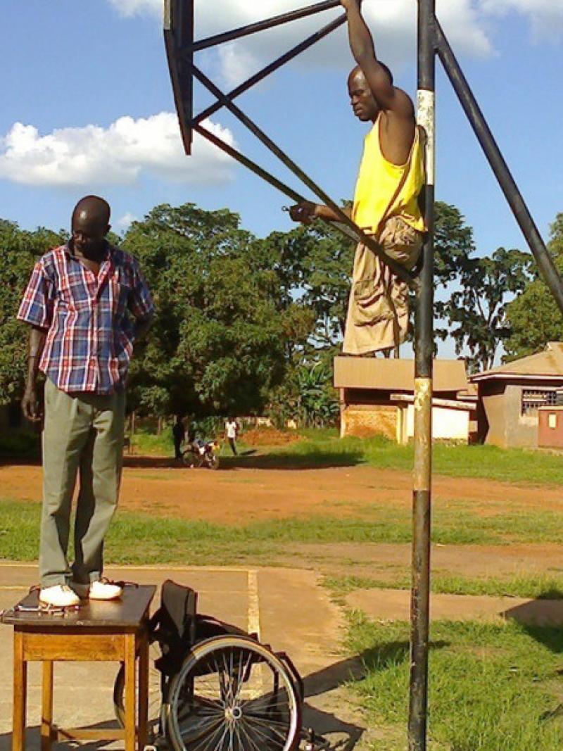 Three Ugandan men prepare the court for wheelchair basketball