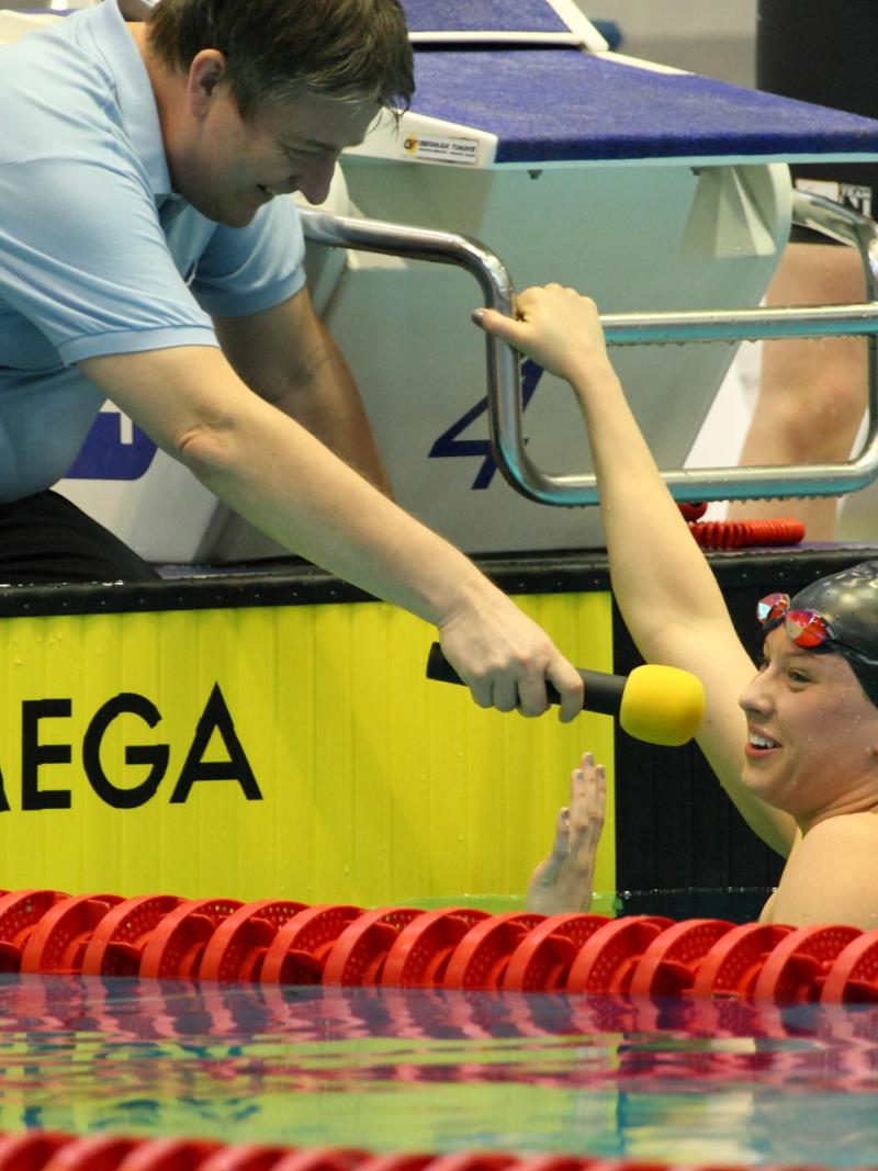 Women in pool giving an interview to someone at the pool edge