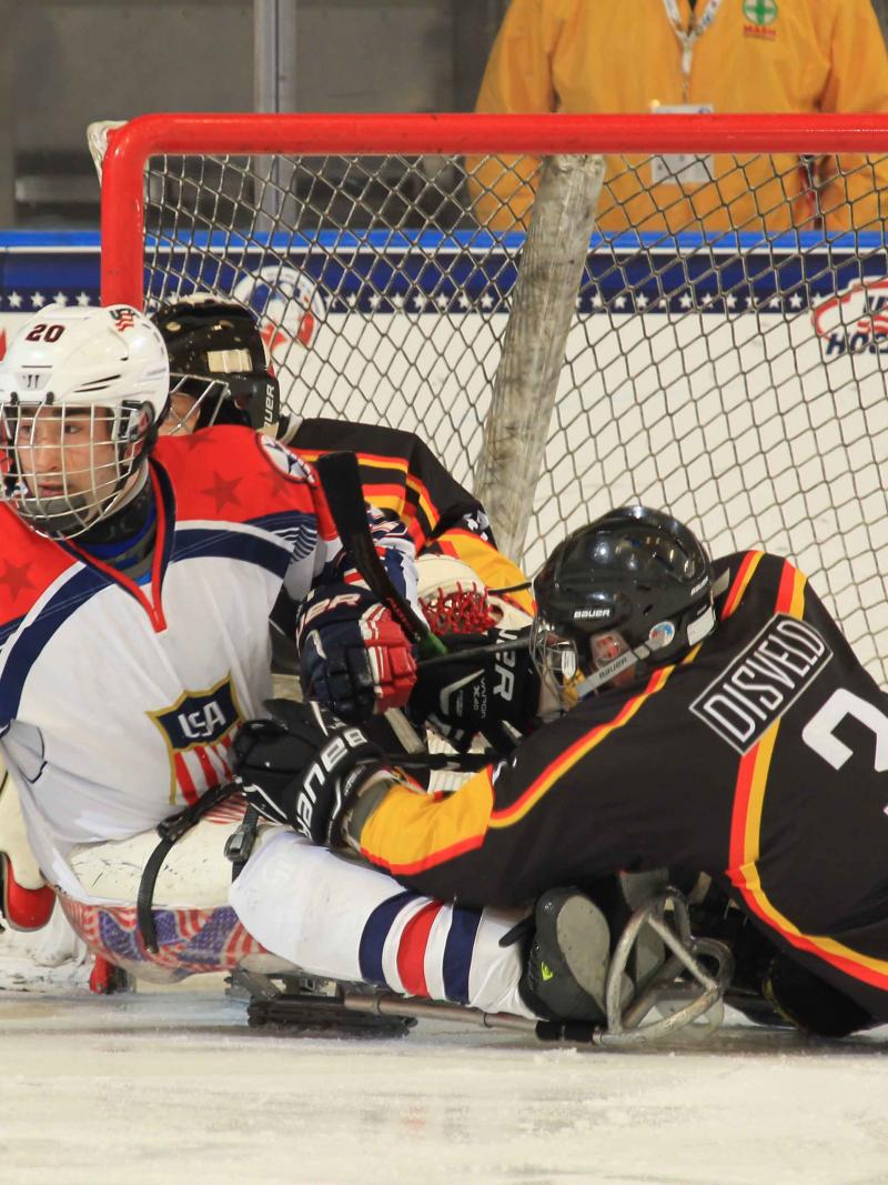 Two ice sledge hockey players fighting for the puck.