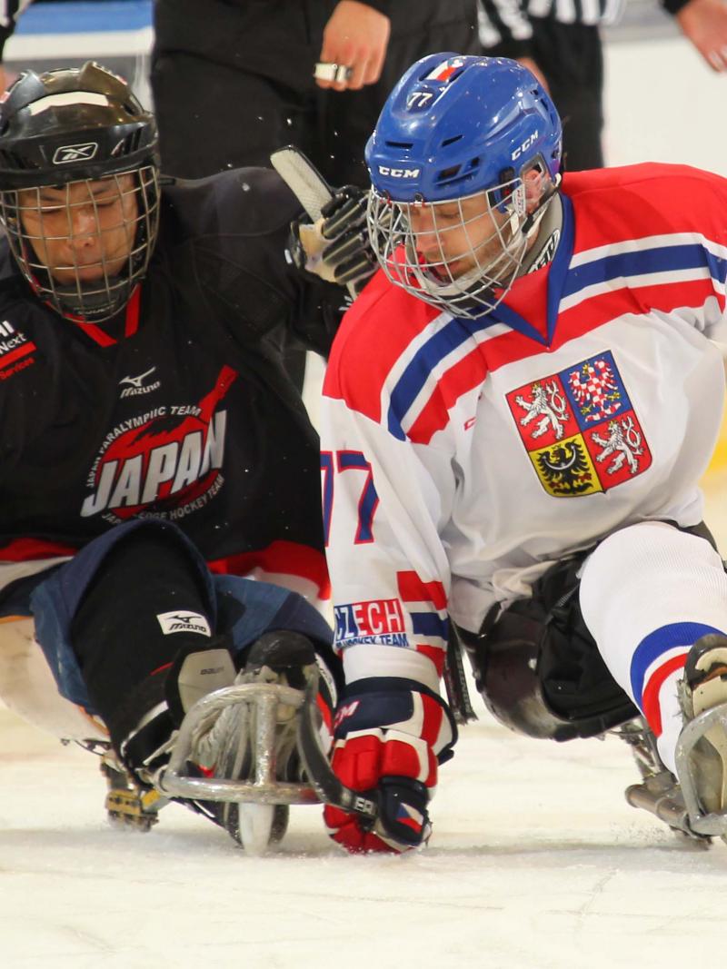 Two sledge hockey players fighting for the puk