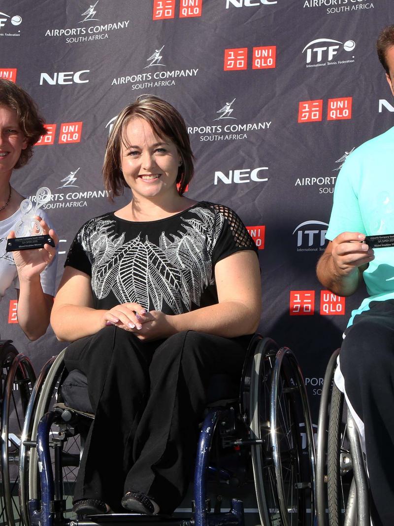 Three people in wheelchairs posing in front of a branded backdrop