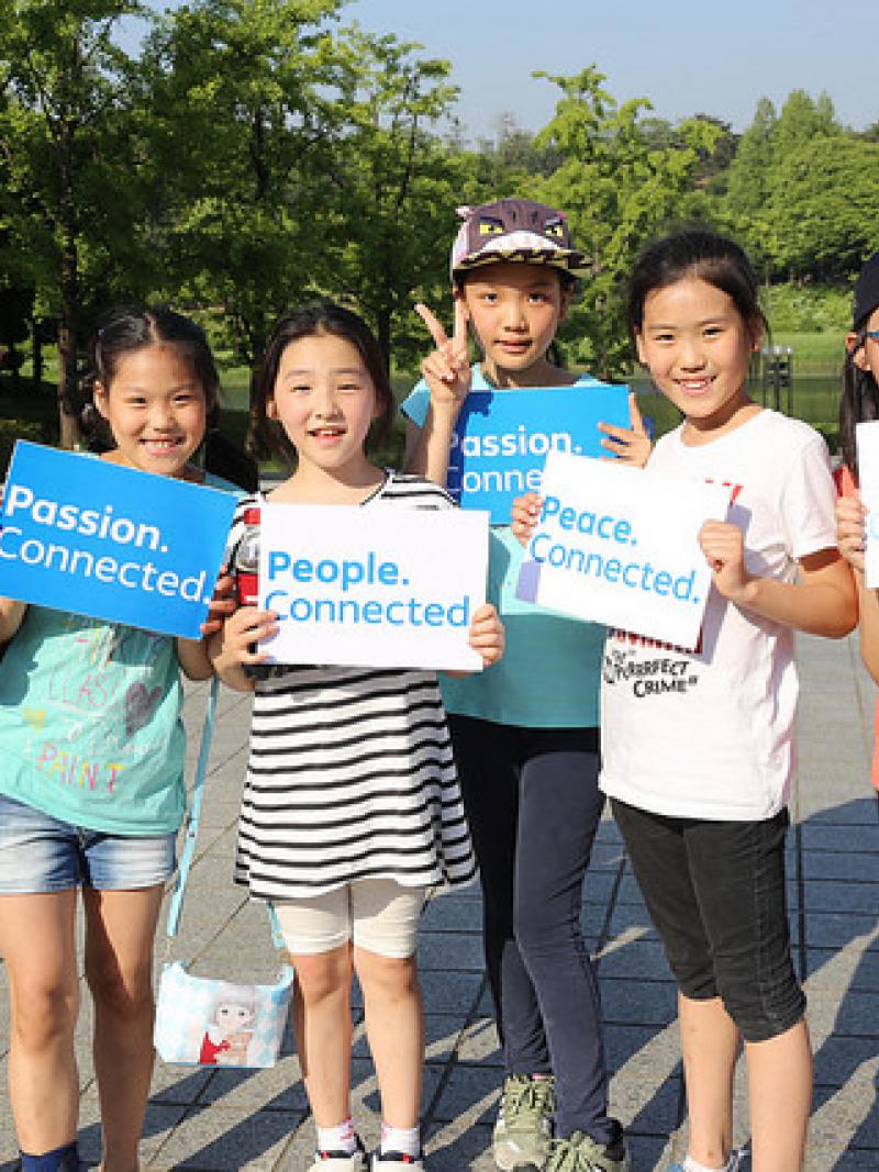 Group of kids showing signs with the words 'Passion. Connected'.
