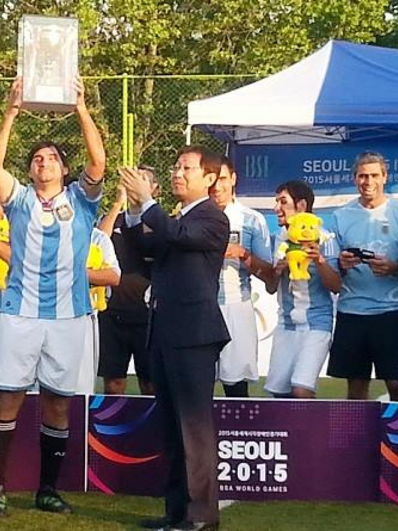 Group of men standing behind a banner holding a cup in the air.