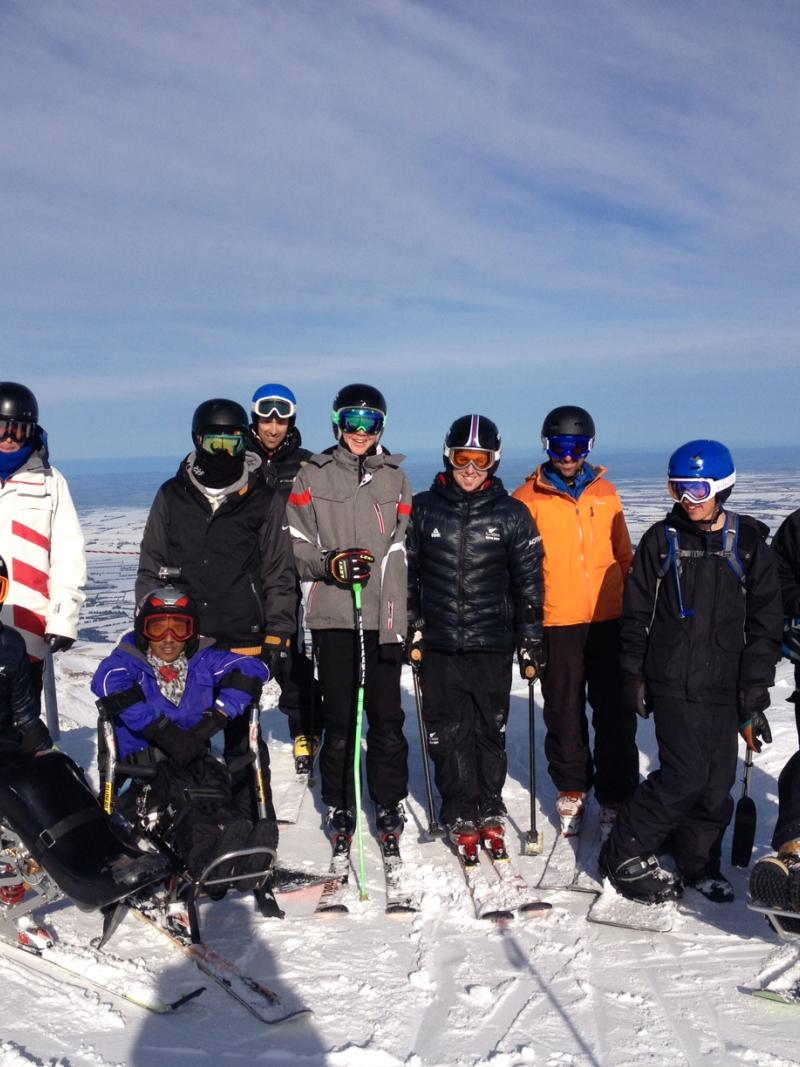 Group shot of skiers (sitting and standing) on a mountain