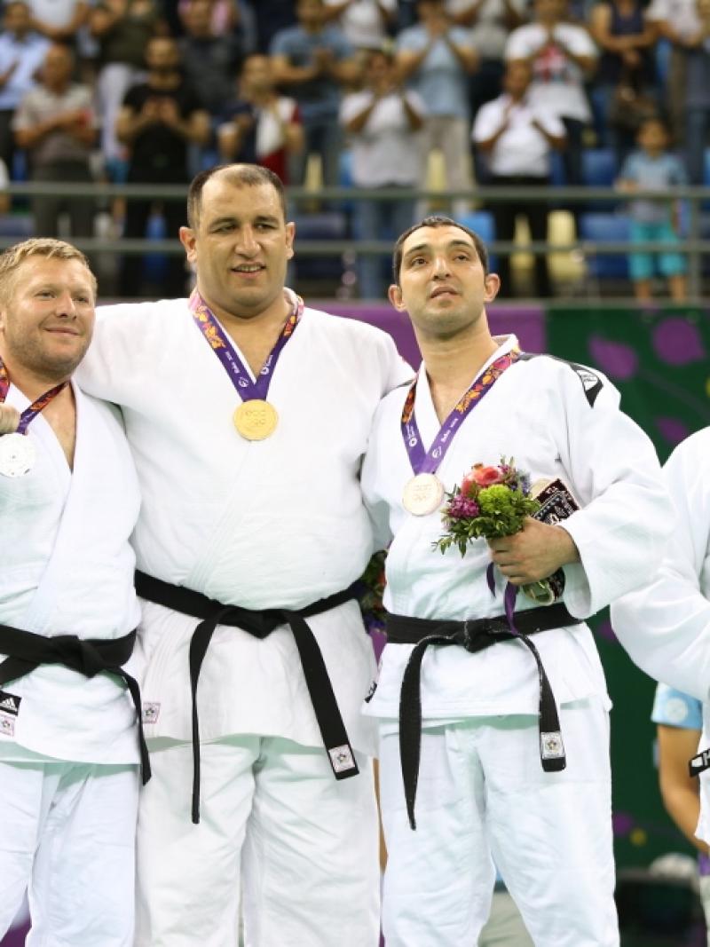 Four male judoka pose on podium