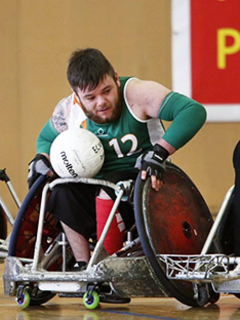 A group of male wheelchair rugby players battling for the ball