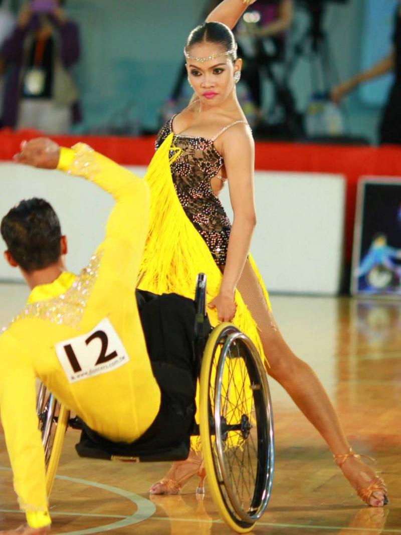Man in wheelchair and woman standing pose while dancing