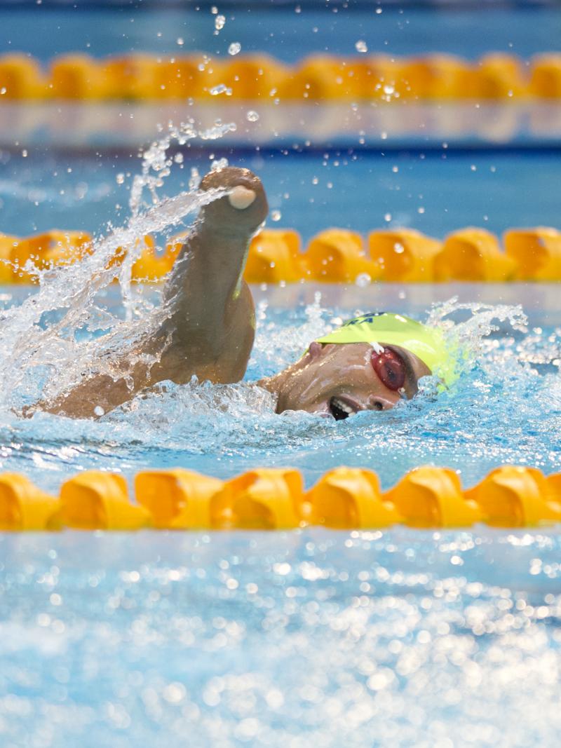 Swimmer with yellow cap doing freestyle.