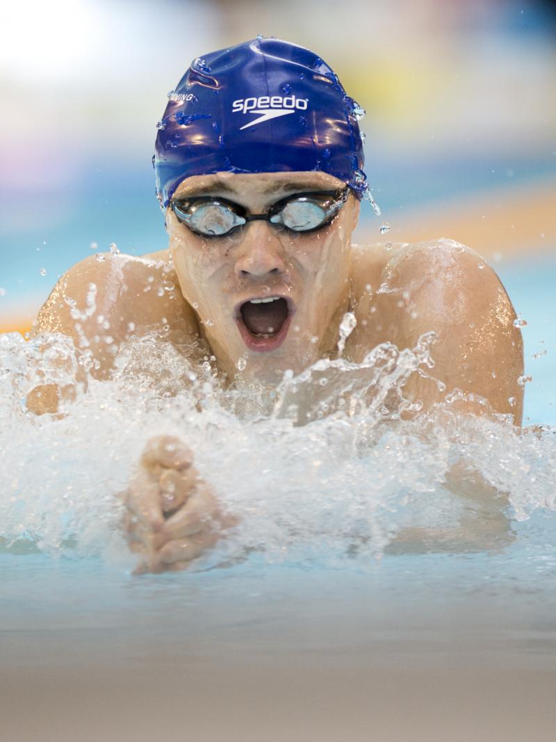 Swimmer with blue swim cap doing breaststroke