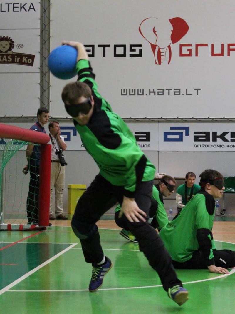 Blindfolded man on a field of play throwing a ball