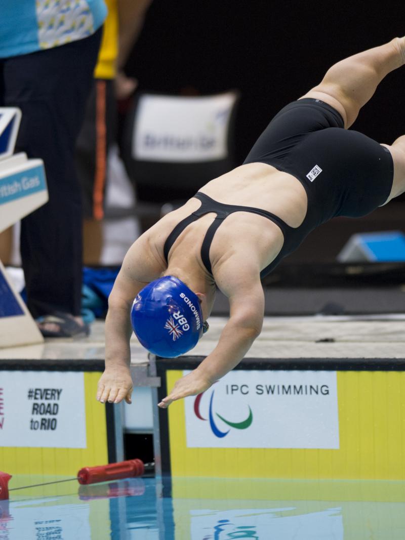 Swimmer with blue swim cap jumps off the start block.
