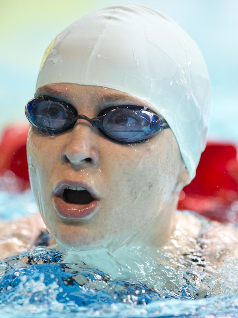 Portrait picture of a swimmer with a white swim cap and swim goggles.