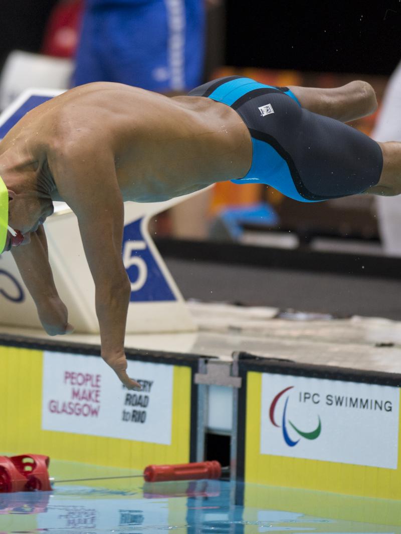 Swimmer with yellow swimp cap jumps of the blocks.