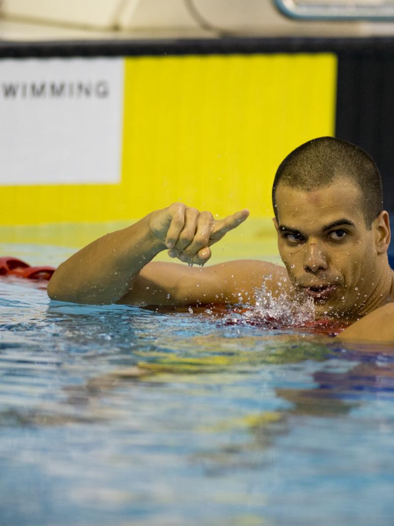 A swimmer stays in the water after finishing a race.