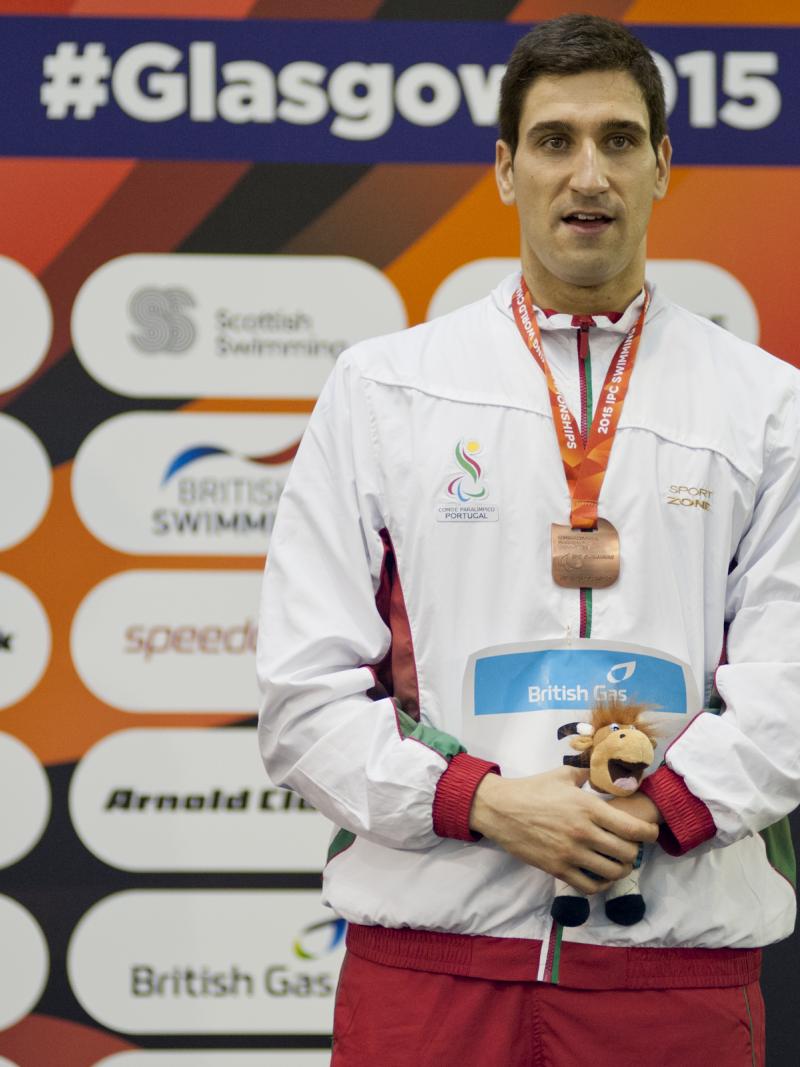 Man with medal around his neck standing on a podium