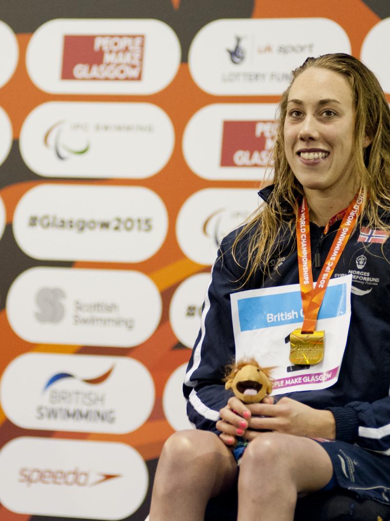 Woman in a wheelchair, on a podium with medal around her neck